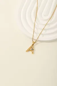 Macro detail of gold letter A pendant with blue stone and sparkling zircons on fine chain