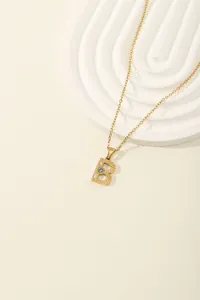 Macro detail of golden letter B pendant with blue zircon and radial texture on o-chain