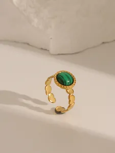 Detailed view of an 18K gold plated ring with a green malachite stone and scalloped band