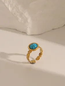 Detailed macro view of an adjustable gold heart-shaped ring with a turquoise stone inlay