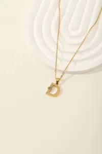 Detail of gold letter D pendant with radial texture and sparkling colored zircons