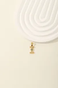 Detailed macro of gold letter I pendant with inlaid blue and white crystals on beige base