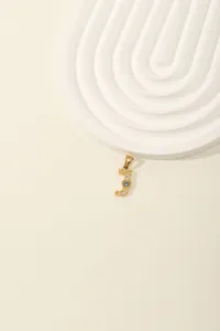 Detail of gold letter J pendant with inlaid white and blue cubic zirconia crystals