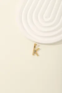 Detail of gold letter K pendant with blue heart gemstone and zircon inlay for women