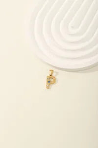 Macro shot of gold letter P pendant with zircon inlay on minimalist O-chain necklace