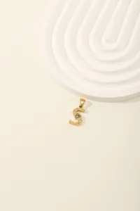 Detail of a gold stainless steel letter S pendant with sparkling zircon stone inlay