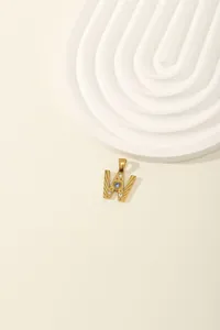 Detail of gold letter W pendant with blue zircon center and textured radial rays