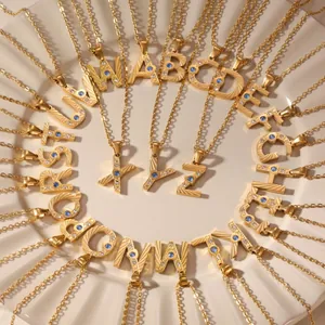 Gold stainless steel initial necklaces with zircon stones on a white ceramic plate