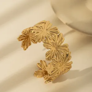 Detail shot of a gold minimalist hammered flower cuff bracelet with daisy motifs