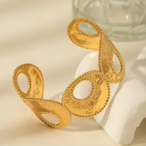 Macro detail of gold hammered texture cuff bracelet with hollowed rings and beaded edges