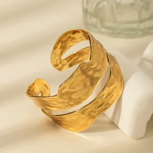 Detailed view of wide gold hammered cuff bracelet with irregular wavy edges and multi-layer texture