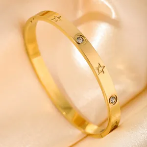 Minimalist gold open bangle with star engravings and cubic zirconia on satin background