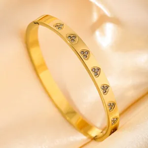 Detail of gold heart engraved bangle with cubic zirconia on luxury silk background