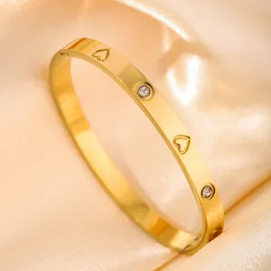 Macro shot of gold plated cuff bracelet with engraved hearts and sparkling zircons