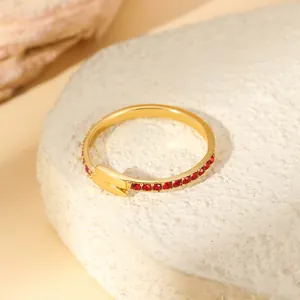 Detail of gold-plated copper ring with red cubic zirconia stones and a geometric link