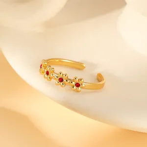 Detail of gold floral open ring featuring tiny red crystals in a delicate vintage style