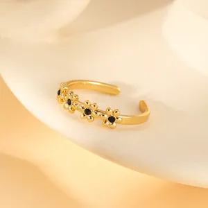 Detail of flower shaped gold ring with black enamel centers and adjustable band