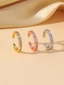 Detailed macro view of three minimalist ear cuffs with pink zircons in a luxury silk setting