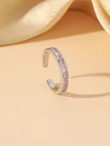 Detail of elegant silver ring with pink zircon inlay on a soft beige silk background