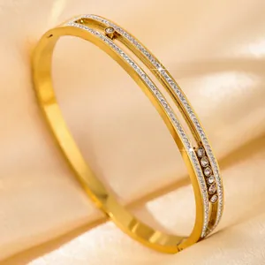 Golden double-track hollow bangle set with white zircons on champagne satin background