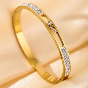 Gold bangle with three sliding zircons in a hollow track on silk background
