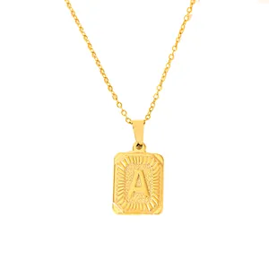 Detail of gold rectangular pendant with letter A and sunburst texture on fine chain