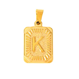 Macro detail of gold-plated rectangular pendant with embossed letter K and sunburst texture