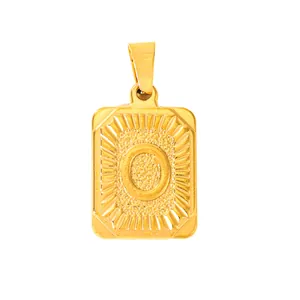 Macro detail of gold-plated rectangular pendant featuring an engraved letter O and sunburst texture