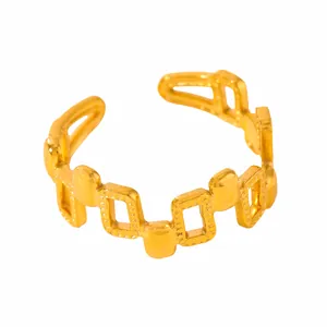 Macro detail of gold-plated geometric ring with square patterns and beaded edge textures