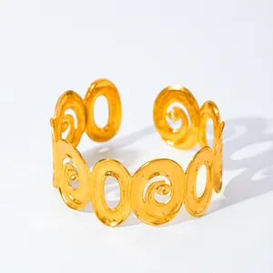 Dettaglio del bracciale rigido dorato con motivi a spirale traforati e finitura martellata
