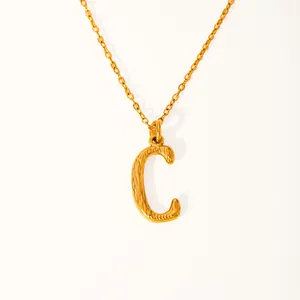 Detail of 18k gold plated letter C pendant with hammered texture and fine chain