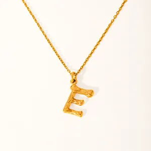 Macro shot of 18k gold plated letter E pendant with detailed bamboo texture and chain