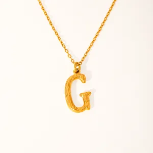 Macro detail of the textured 18k gold plated letter G pendant on a thin chain link