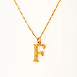 Detailed close-up of golden letter F necklace with unique textured metallic surface
