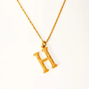 Macro detail of gold-plated H-letter pendant featuring unique bamboo-style carved textures