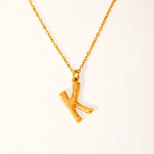 Close-up of golden K-letter pendant with natural bamboo texture on a fine chain