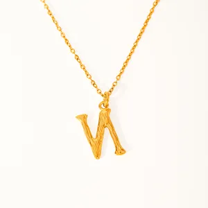 Macro detail of 18k gold plated letter V pendant with unique hammered metal texture