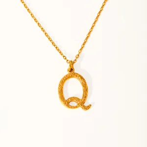 Detail of 18k gold plated letter Q pendant with hammered texture on a slim chain necklace