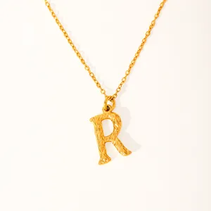Macro detail of 18k gold plated letter R pendant featuring a unique bark texture design