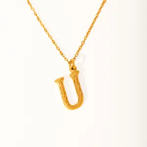 Detail of 18k gold plated letter U pendant featuring a unique bark texture finish