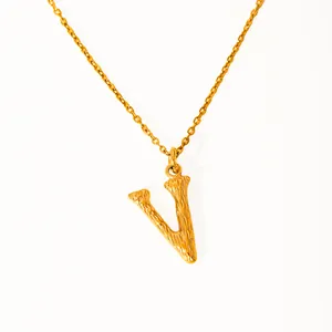 Macro shot of 18k gold plated V letter pendant with unique bark texture finish