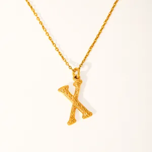 Macro detail of the gold-plated 18k letter X necklace showing woven rope texture