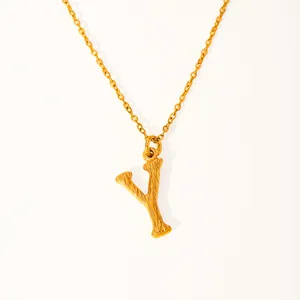 Close-up of golden letter Y pendant with wood-grain texture and delicate cable chain