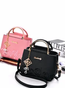 Detalle de bolsos de cuero elegantes con bordado de rosas, asas de metal y colgantes