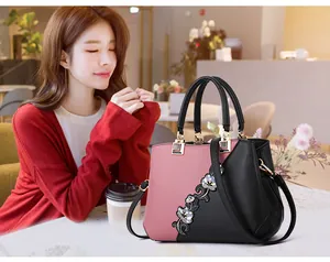 Close-up of pink and black color-block handbag featuring elegant floral embroidery details