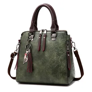 Vintage dark green faux leather handbag with brown handles and a cat charm pendant