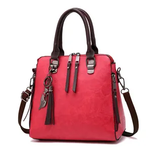 Red pebbled leather handbag with brown handles and cat-shaped pendant detail