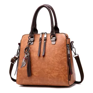 Classic brown PU leather handbag with cat pendant and fringe zippers on white background