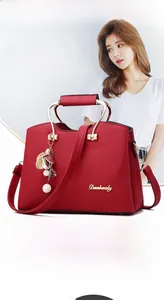 Close-up of red lychee grain leather tote bag with unique circular metal handle and charms