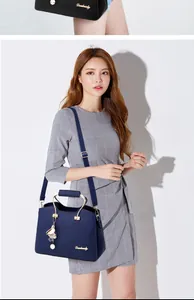 Detail of navy blue leather handbag with golden metal handle and plush floral charm